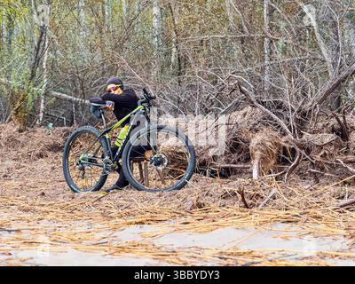 Riga, Latvia - May 3, 2025: A skillfully cyclist resting around beautiful wooded area with mountain bike Stock Photo