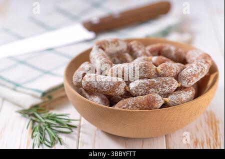 Mini salami sausages in a bowl on a white wooden table. Mini Chorizo. Stock Photo