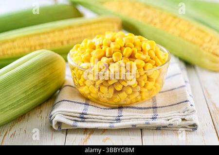 Canned food maize in a clear glass bowl on a white kitchen table, selective focus. Stock Photo