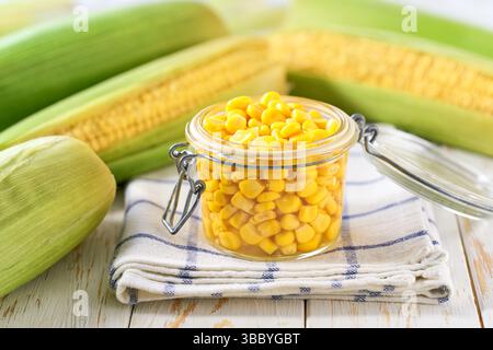 Canned sweet corn in jar on a white table, selective focus. Stock Photo