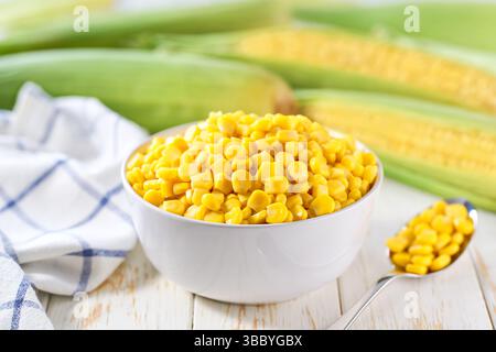 Canned sweet corn kernels in the bowl on a white table, selective focus. Stock Photo