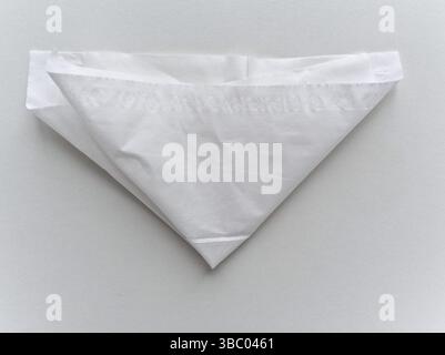 A white paper is folded into a triangle. The paper is white and has a pattern on it Stock Photo
