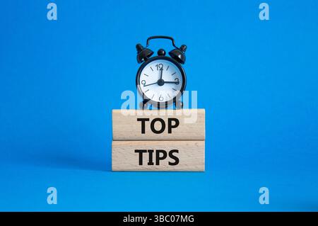 Top Tips symbol. Concept words Top Tips on wooden blocks. Beautiful blue background with alarm clock. Business and Top Tips concept. Copy space. Stock Photo