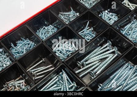 A box of new steel screws of various sizes placed in plastic cells. Stock Photo