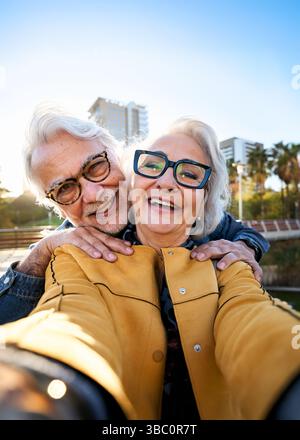 Happy senior couple taking a selfie in the city park Stock Photo