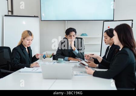 Diverse business team engaged in a focused strategy meeting, analyzing data and discussing solutions to enhance collaboration. Stock Photo
