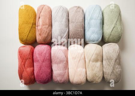 The set of threads for knitting that arranged in two horizontal rows. Threads in pastel colors lie on a white background Stock Photo