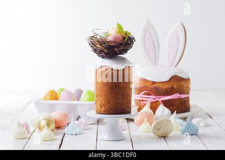 In the foreground an Easter cake decorated with a nest on the top. Painted eggs in the nest. In the background is another Easter cake with bunny ears Stock Photo