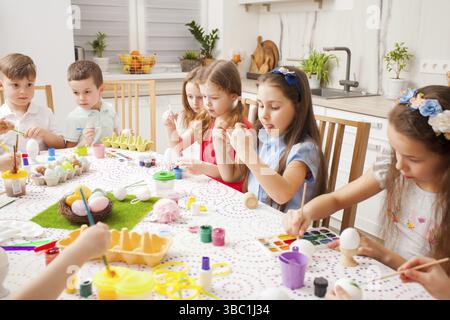 Happy childred painting eggs together. Friends preparing for Easter. Teamwork concept Stock Photo