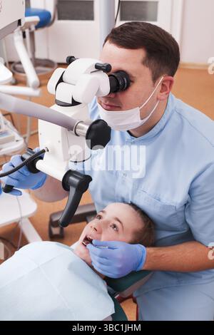 Dentist looking through magnifying glass. He's using microscope for operation at dentist office Stock Photo