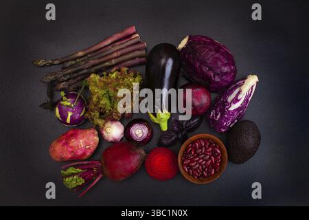 Heap of raw purple vegetables on the black background. Top view, flat lay Stock Photo