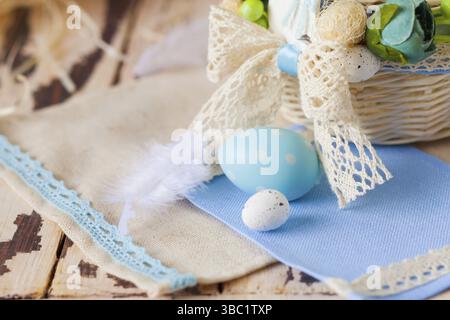 Close-up macro cute ceramic Easter eggs laying on handcrafted napkins. Small wicked basket decorated with handmade crochet lace. Cracked wooden surfac Stock Photo