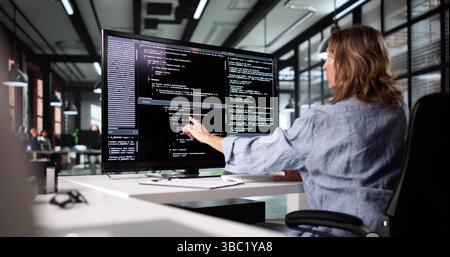 Female Web Developer Working On Software Code At Office Desk Stock Photo