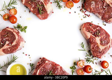 Raw pieces of ribeye steak with spices and various ingredients. Meat with ingredients laid out on a white background Stock Photo
