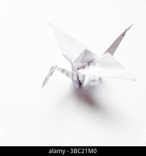 The origami crane is made of white paper, isolated on a white background Stock Photo