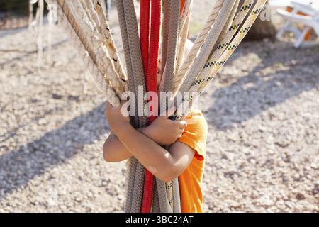 Boy holds many ropes on the marine playground at the sea cost Stock Photo