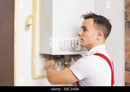 The side view of a young plumber installing a boiler Stock Photo