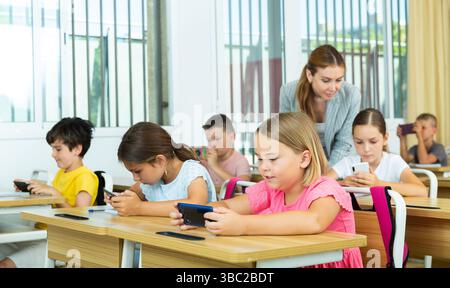 Pupils using mobile phones during lesson in school Stock Photo