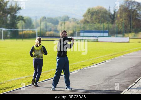 Man and a woman in sportswear doing sport exercises at the stadium Stock Photo