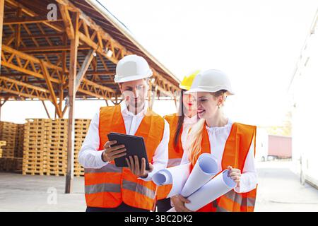 Group of young architects and engineers in helmets and plan on building. Love affair at work Stock Photo