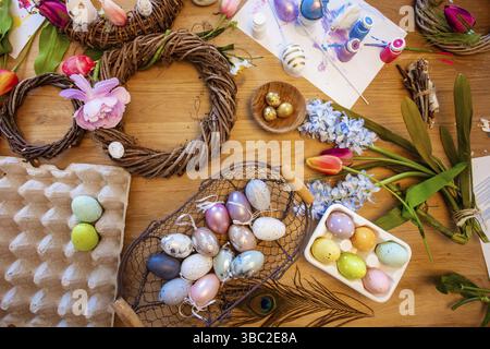Top view many details of Easter decorating set on wooden surface. Wreaths made of branches, colorful Easter eggs and artificial flowers. Creative East Stock Photo