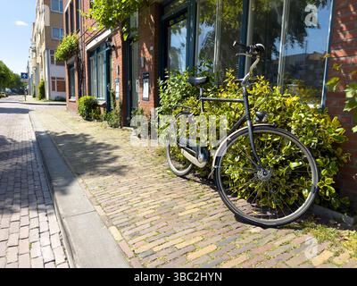 Bicycle parked on sidewalk in front of brickwall building in Delfshaven. Biking in Netherlands Holland Stock Photo