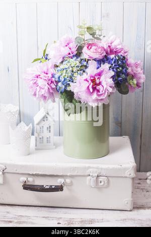 Flowers in a blue vintage can on white retro bag and kitchen earthenware Stock Photo