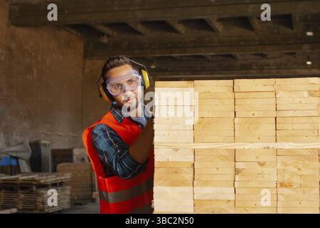Busy young professional woodworker using equipment wooden plank at workshop Stock Photo