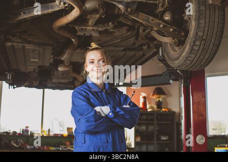 Confident smiling auto mechanic woman in overalls at garage Stock Photo