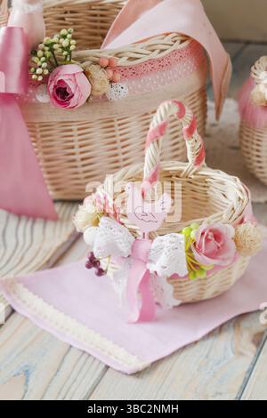 Two decorative wicker basket in nice light pink style, with original decor made of flowers and laces. Stylish floral decor on baskets, handmade Stock Photo