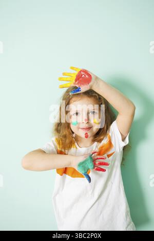 Portrait of cute girl with painted face and hands colored with watercoloros Stock Photo
