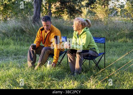 Man and woman enjoying warm beverages in outdoor setting Stock Photo