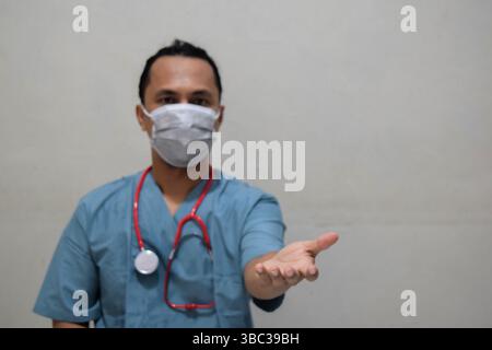 Young doctor man holding something on gray background Stock Photo