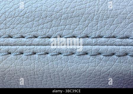 Macro photograph of a white leather surface showcasing intricate stitching and textured material. Ideal for use in design, upholstery, or material rep Stock Photo