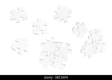 Scattered white puzzle pieces on a white background. Some pieces are connected, while others are separate, creating an unfinished arrangement. Stock Photo