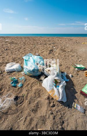 Plastic bags and bottles littered on a sandy beach by the sea Stock Photo