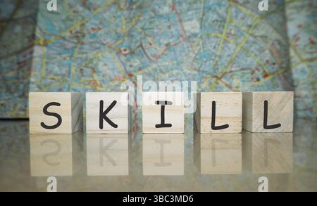 The letters SKILL are written on a wooden block. The block is placed on a table. The letters are black and white Stock Photo