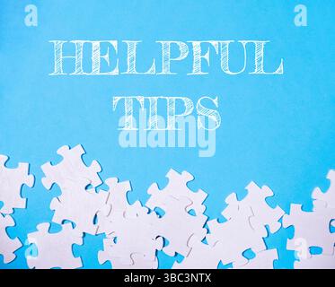 Blue background with white puzzle pieces and the words helpful tips written in white Stock Photo