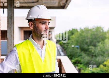Construction engineer wearing safety helmet and vest inspecting building site Stock Photo
