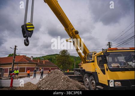Orastioara de Sus, Romania - May 12, 2025: Yellow Mobile Crane on a Construction Site in Rural Romania. Stock Photo