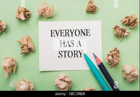 Piece of paper with the words everyone has a story written on it. There are also two pens on the paper Stock Photo
