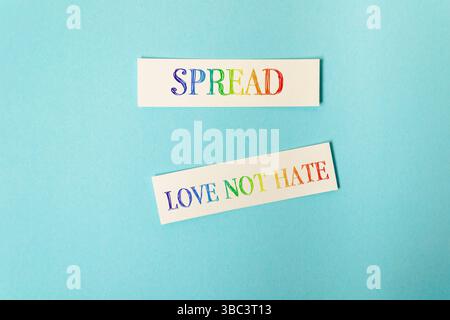 Two stickers with the words spread and love not hate on them. They are on a blue background Stock Photo