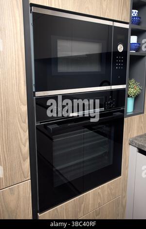 Contemporary fitted kitchen interior with minimalist flat design. Built-in oven and microwave oven in flat design wooden kitchen furniture. Selective Stock Photo