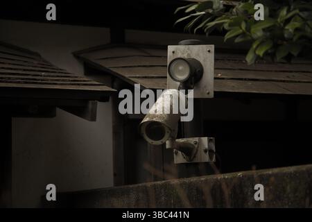A security camera mounted on a traditional Japanese building, contrasting modern surveillance with old architecture Stock Photo
