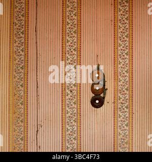 Intricate floral designs and charming stripes decorate the walls of an old building, while three circular buttons of old switch Stock Photo