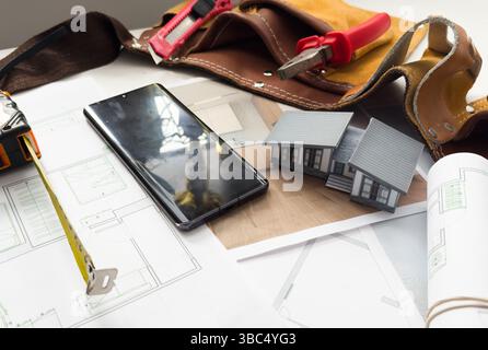 Architectural model on desk with smartphone, drawing technical tools and blueprints. Architecture, building, construction and real estate business. Stock Photo