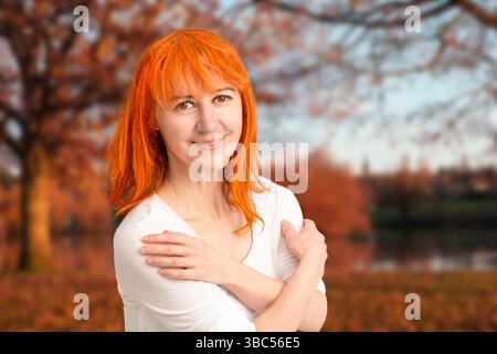 Portrait of a red-haired woman in front of an orange autumn landscape Stock Photo
