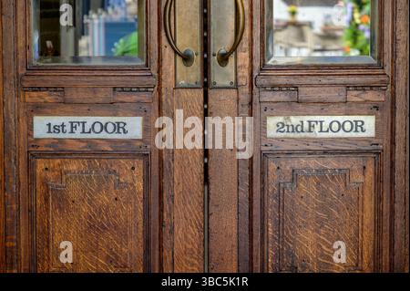 First and second floor signs on external wooden doors, UK Stock Photo
