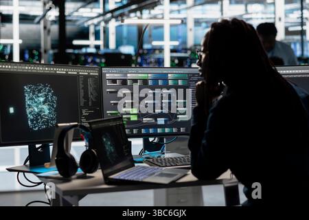 Data center engineer implements AI driven virtualization frameworks to optimize server clusters. Server hub employee does artificial intelligence predictive analysis using visual programming Stock Photo