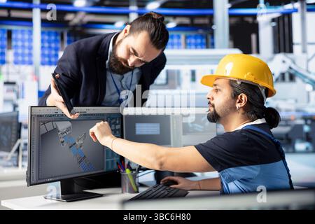 Photovoltaics factory manager supervising specialist creating CAD models for solar modules. Team leader overseeing work done by man developing and optimizing solar panel designs Stock Photo